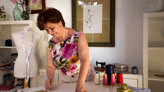 Mari Carmen trazando un patrón sobre la mesa